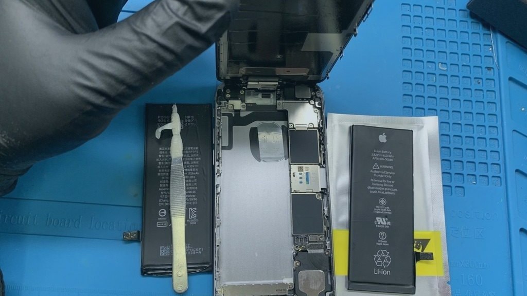 iPhone abierto en el taller de EspecialistaMac con la batería gastada retirada y la nueva lista para instalar