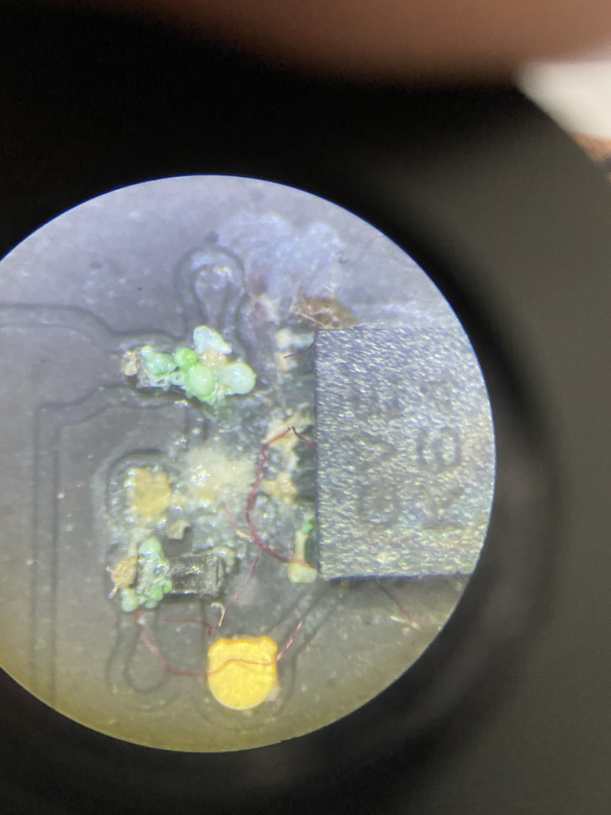 Corrosión avanzada por líquido alrededor de un chip de una placa de MacBook, con residuo blanco y verde sobre varios componentes