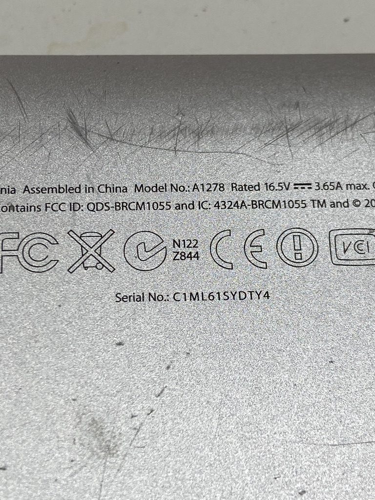 Tapa inferior de una MacBook Pro con el número de modelo A1278 y el número de serie impresos en letra pequeña