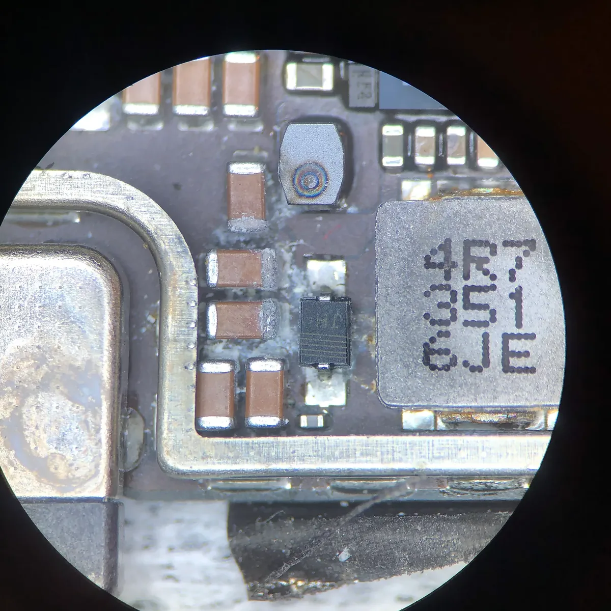 Vista por el microscopio de una placa con restos blancos de corrosión entre los componentes.