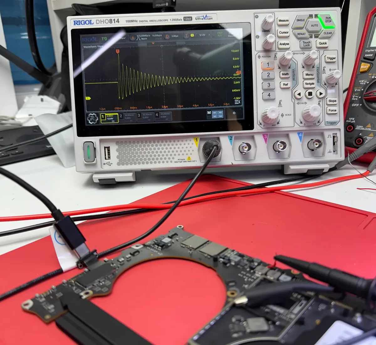 Osciloscopio midiendo una señal sobre una placa lógica conectada con puntas de prueba.