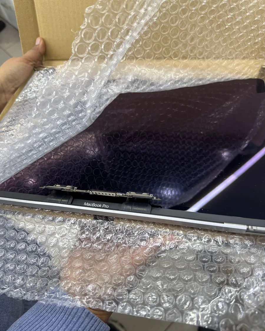 Display de MacBook Pro envuelto en plástico de burbujas dentro de una caja de cartón.