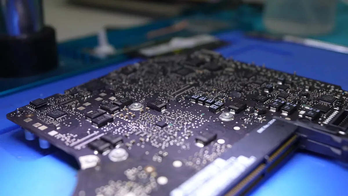 Placa lógica de una MacBook vista de cerca sobre el tapete azul.