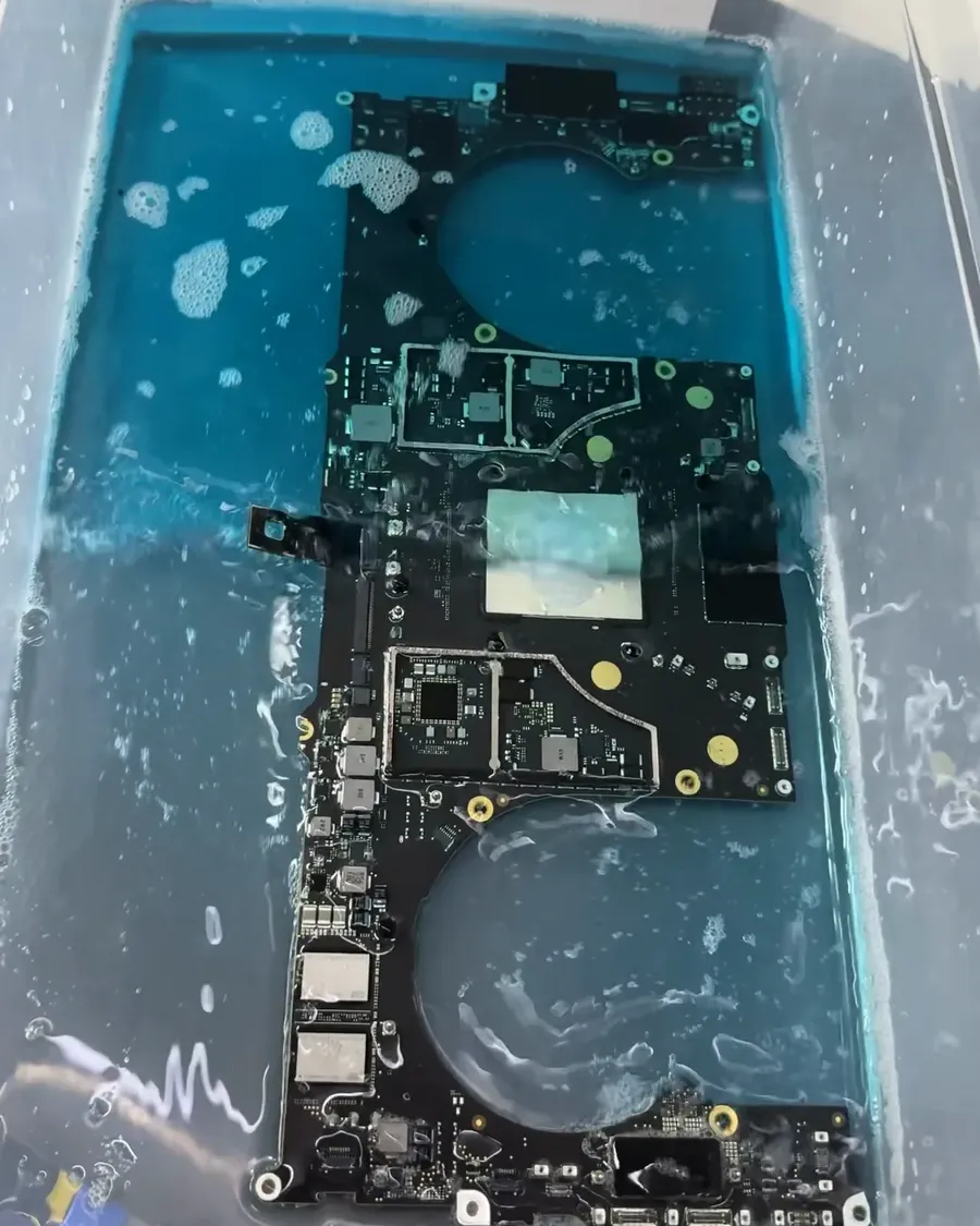Placa de MacBook sumergida en el baño de limpieza.
