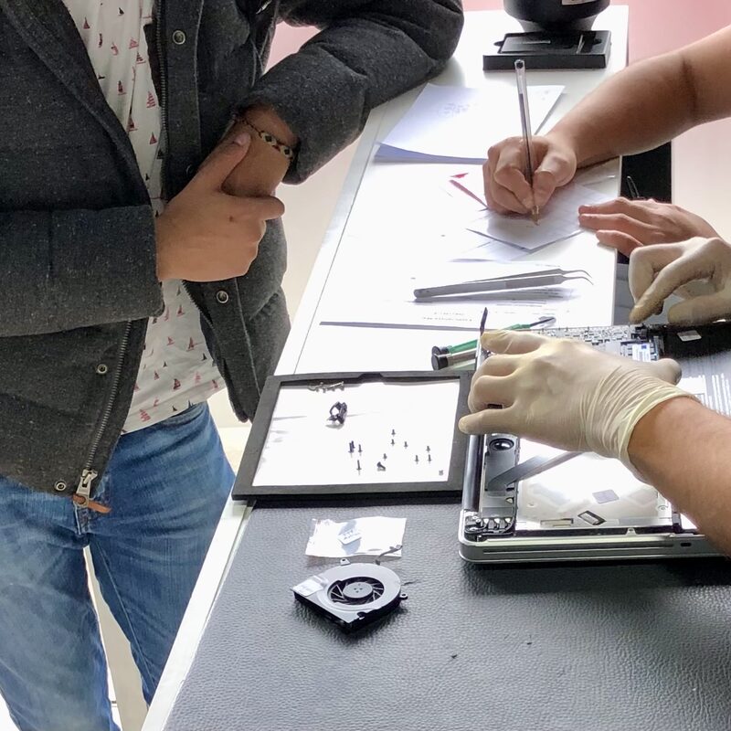 Sesión de diagnóstico — técnico documentando hallazgos mientras desarma un MacBook con guantes