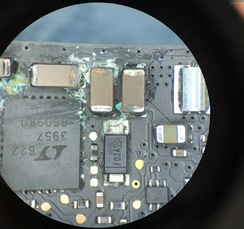 Vista por el microscopio de componentes con corrosión verde en el borde de una placa