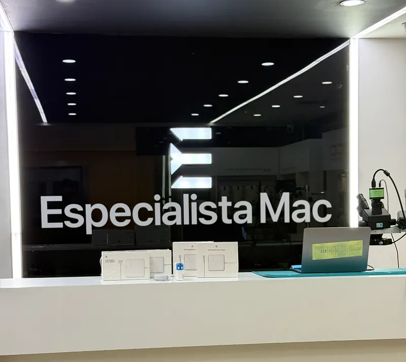 Mostrador blanco del local con el letrero de EspecialistaMac sobre vidrio negro y cargadores en exhibición